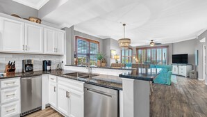 A modern kitchen with white cabinets, stainless steel appliances, and a granite countertop. - 101 West - Beachfront 3BR/3BA Corner Condo! (Gulf Shores)