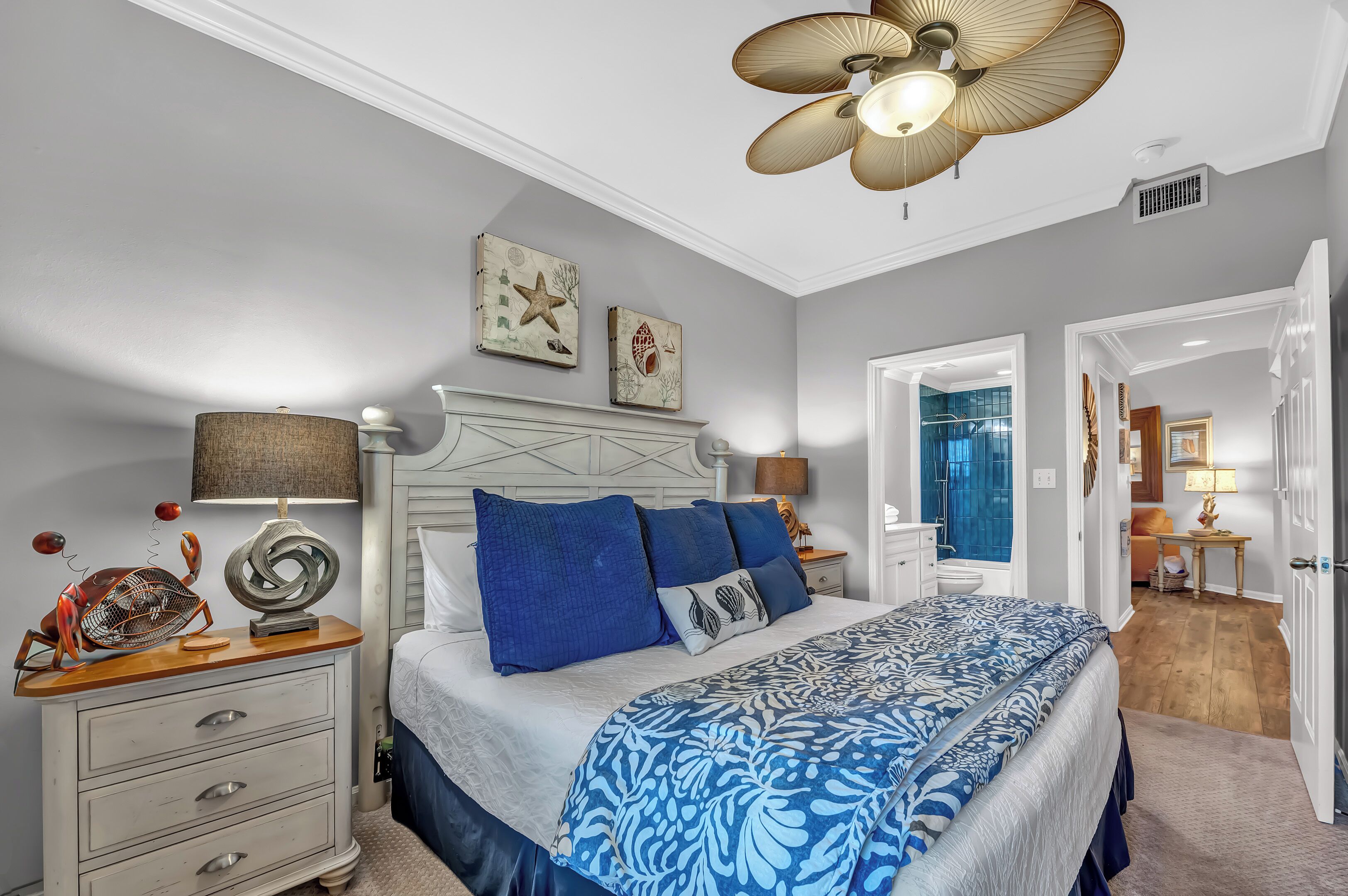 A bedroom with a bed, bedside tables, a ceiling fan, and wall art.