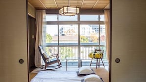 A room with a bed, a rocking chair, and a chair with a cushion. - Next International Homestay (Takamatsu)