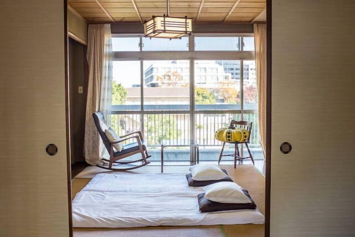A room with a bed, a rocking chair, and a chair with a cushion.