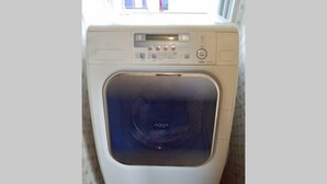 A front view of a white washing machine with a digital display and control panel. - Next International Homestay (Takamatsu)