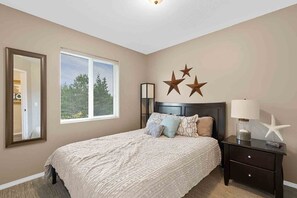 A bedroom with a large bed, a nightstand, a lamp, and a mirror.