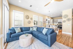 A living room with a sectional sofa, a round coffee table, and a kitchen in the background.