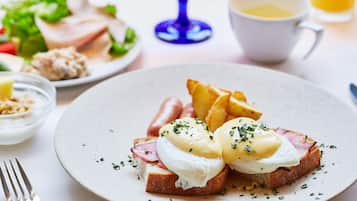A breakfast plate with eggs, ham, and potatoes.