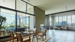 A spacious living area with large windows, a high ceiling, and a view of the city skyline. - Mitsui Garden Hotel Gotanda Tokyo (Tokyo)