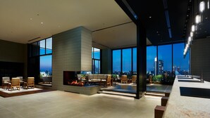 A modern living room with a fireplace, comfortable seating, and large windows offering a city view. - Mitsui Garden Hotel Gotanda Tokyo (Tokyo)