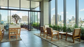 A modern interior with large windows, a seating area with wooden furniture, and a view of the cityscape. - Mitsui Garden Hotel Gotanda Tokyo (Tokyo)