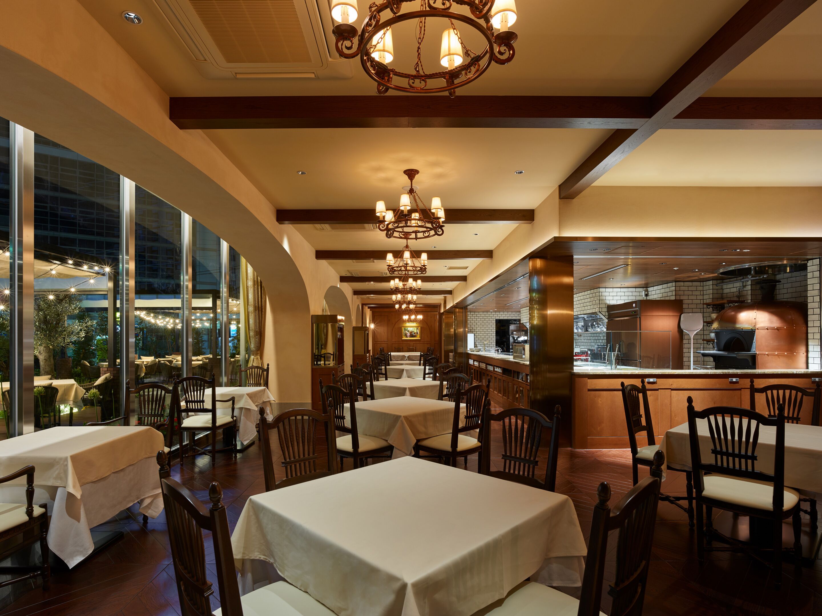 A restaurant interior with tables, chairs, a bar area, and a view through large windows.