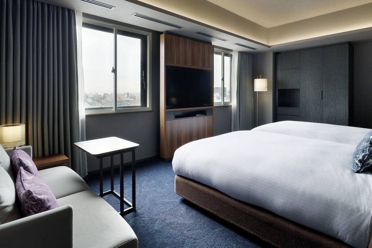 Ein Hotelzimmer mit einem großen Bett, einem Fernseher, einem Schreibtisch und einem Sessel.