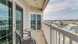 Un balcon avec une porte vitrée, une chaise en osier et une petite table.