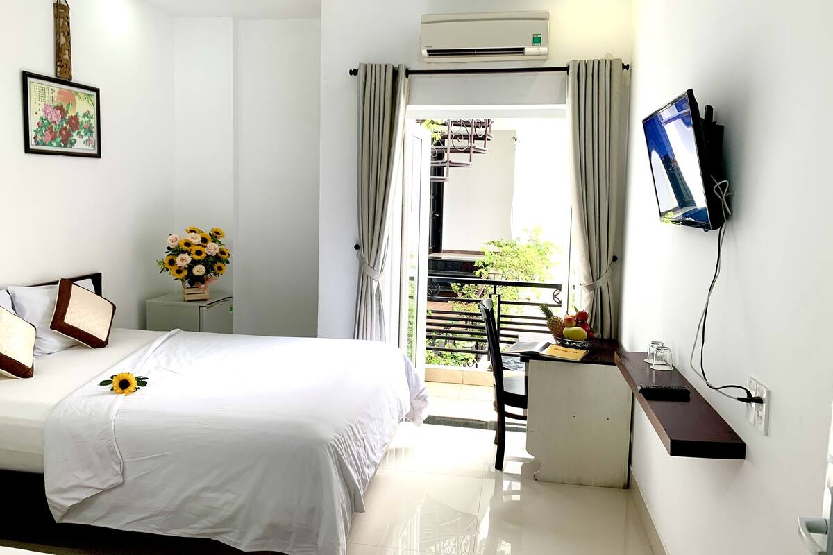 Habitación de hotel con una cama, un escritorio con silla, un televisor y un aire acondicionado.