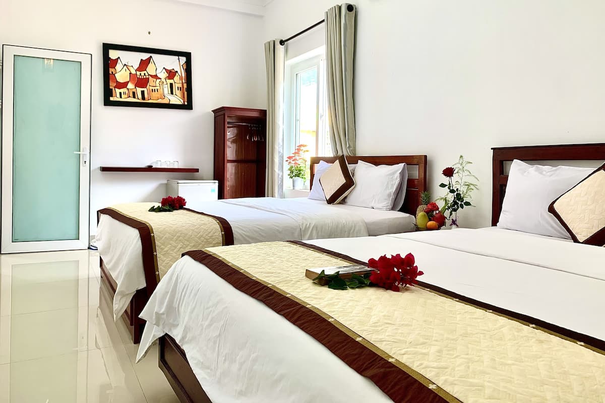 Habitación de hotel con dos camas, un armario, una mesita y un cuadro en la pared.