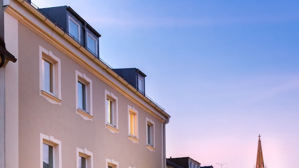Um hotel com várias janelas, uma fachada visível e uma rua de paralelepípedos.
