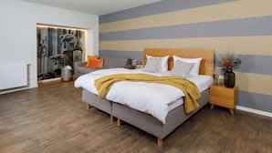 Un dormitorio moderno con una cama grande, una mesita de noche, un sofá y un adornado en la pared.