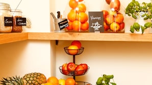 Uma bancada de cozinha bem organizada com diversas frutas, uma abacaxi, muffins e uma tigela de morangos.