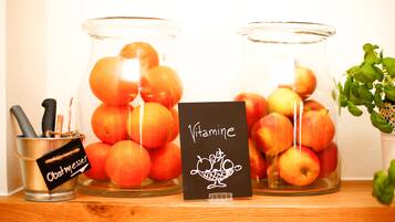 Two glass jars filled with oranges and apples, a metal container with a label, and a card with the word "Vitamine".