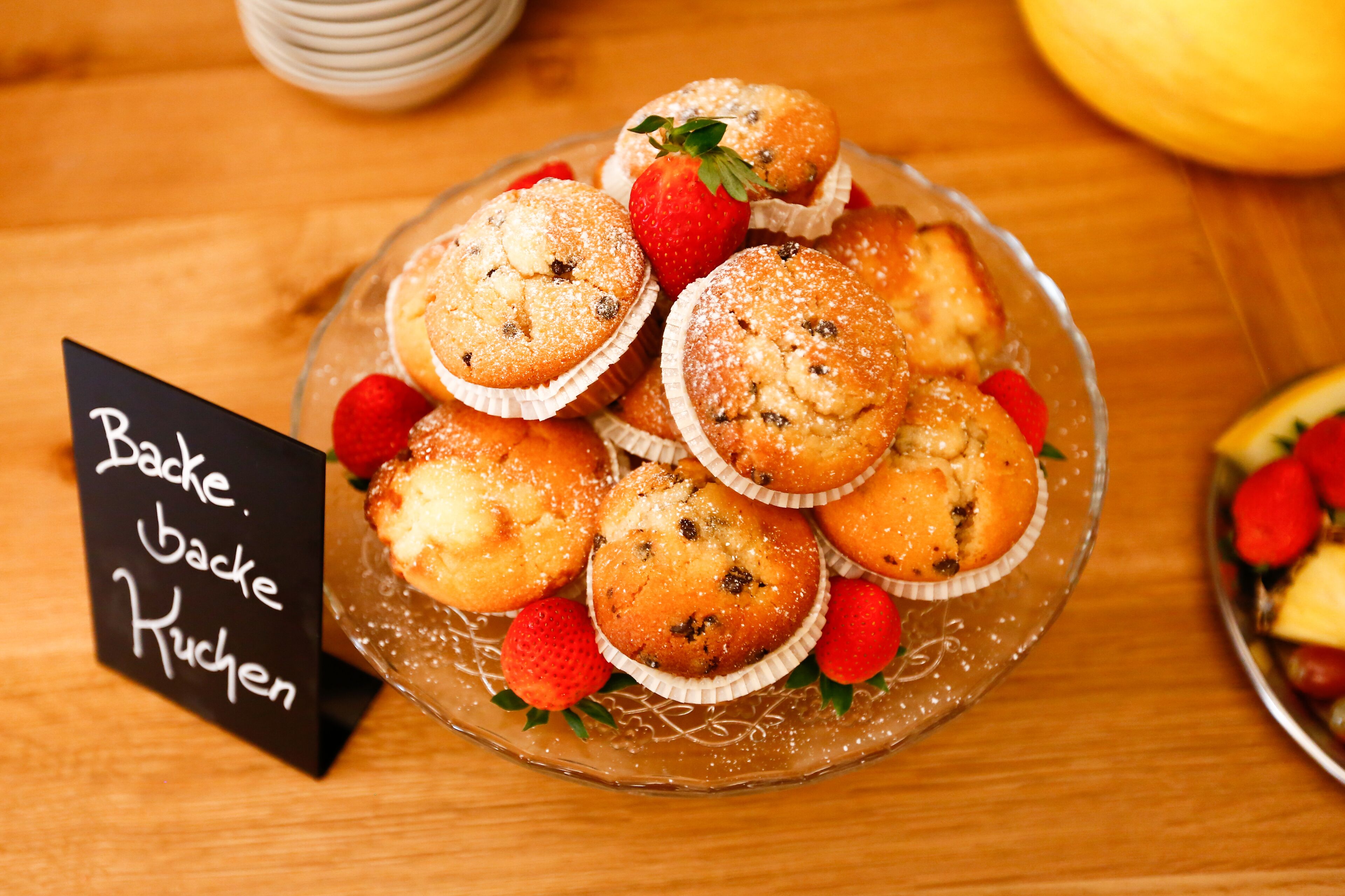 A glass plate with muffins and strawberries.