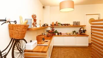 A kitchen with wooden cabinets, a hanging basket with bread, and a bicycle.