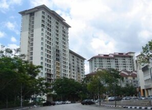 A high-rise residential building with multiple floors, surrounded by trees and parked cars. - Vibrant Studio at Damansara Perdana (Petaling Jaya)
