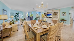A spacious dining area with a wooden table set for six, surrounded by wicker chairs.