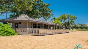 Un edificio frente a la playa con un porche cubierto y una playa arenosa al frente.