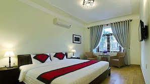 A hotel room with a large bed, two bedside tables, a desk with a chair, a window with curtains, and a wall-mounted TV. - An Hoi Town Homestay (Da Nang)