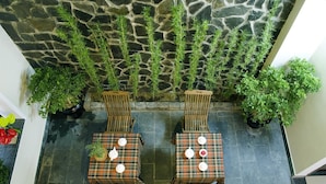 An outdoor seating area with two tables and four chairs, surrounded by potted plants and a stone wall. - An Hoi Town Homestay (Da Nang)