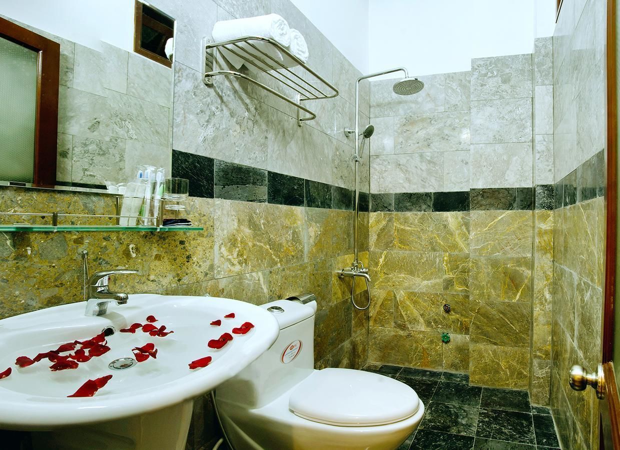 A bathroom with a marble sink, toilet, and shower.