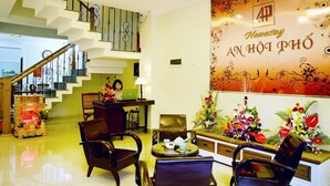 A hotel lobby with a staircase, seating area, and a reception desk. - An Hoi Town Homestay (Da Nang)