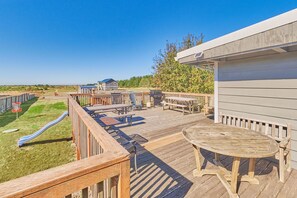 A wooden deck with picnic tables and a barbecue grill.