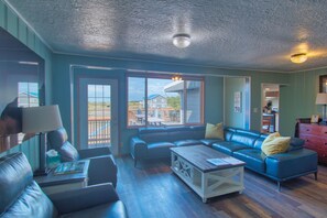 Ein geräumiges Wohnzimmer mit einem blauen Ledersofa, einem Holztisch und Blick ins Freie.