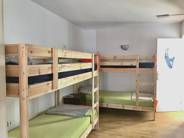 Una habitación con tres literas, una mesita pequeña y un espejo en la pared.