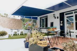 An outdoor patio area with tables and chairs, a sign that says 'SLOW DOWN,' and potted plants. - Endless Summer House - Hostel adults only (Adeje)