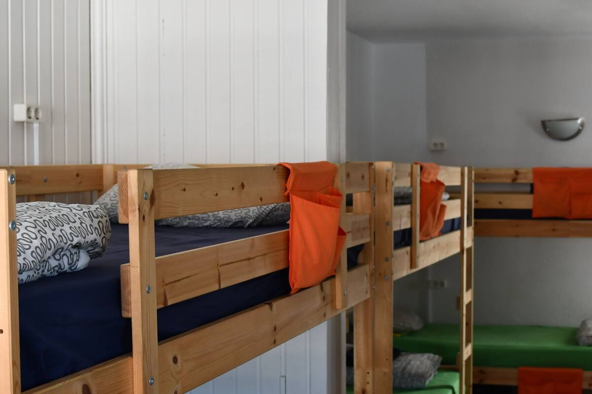 A room with bunk beds, each with a pillow and a blanket.
