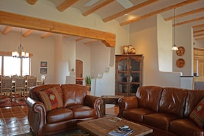 A spacious living room with leather sofas, wooden beams, a dining area with chairs, and a kitchen in the background. - Mountain View- Great Views Enclosed Patio with Private Hot Tub Pool Table (El Prado)