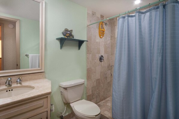Un baño con inodoro, lavamanos y cortina de ducha.