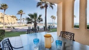 Una mesa con sillas y vistas a una piscina y palmeras.