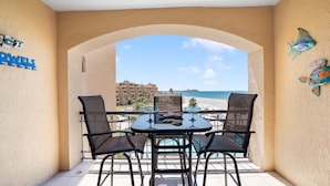 Un balcon avec une table et des chaises, une vue sur la plage et une enseigne indiquant « POWELS ».