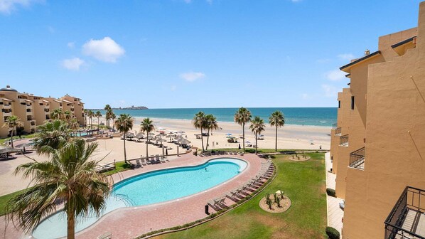 Un complexe hôtelier doté d’une piscine, d’une plage et de palmiers.