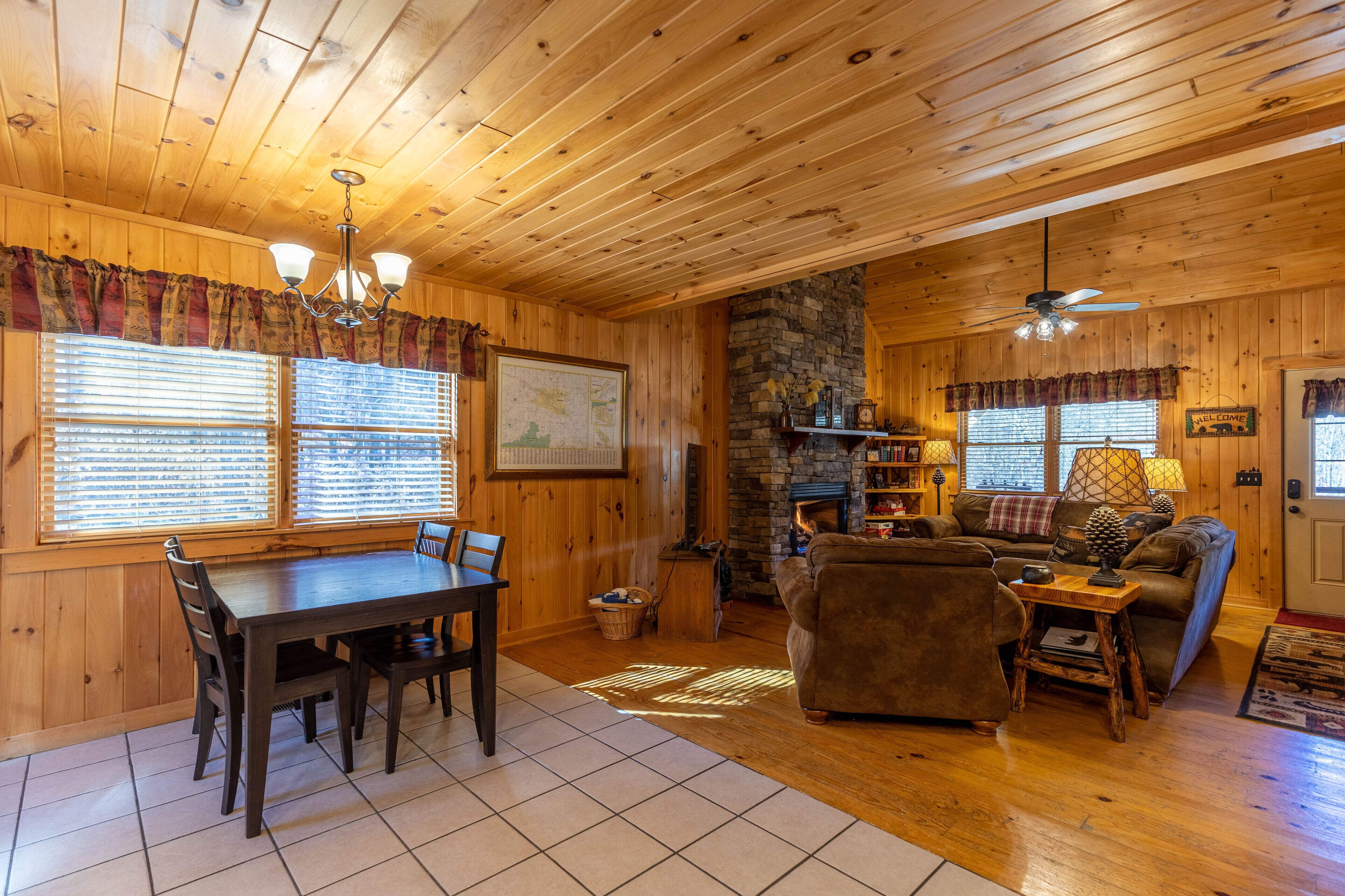 A cozy cabin interior with a dining area, fireplace, and seating.