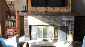 A cozy living room with a fireplace, a flat-screen TV mounted above it, and comfortable seating.