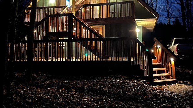 A two-story wooden cabin with a balcony and a staircase leading to the upper floor.