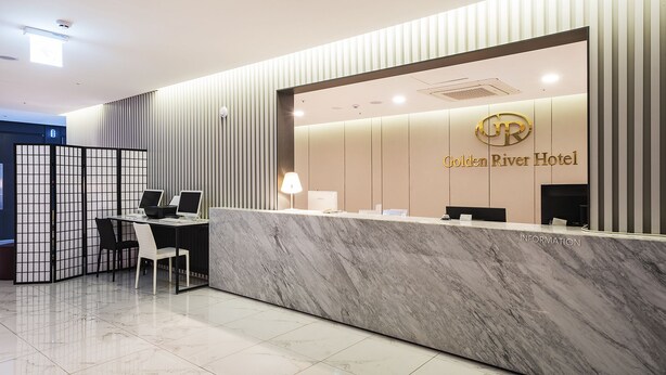 A hotel reception desk with a marble counter, a computer, and a seating area. - Golden River Hotel (Gwangmyeong)