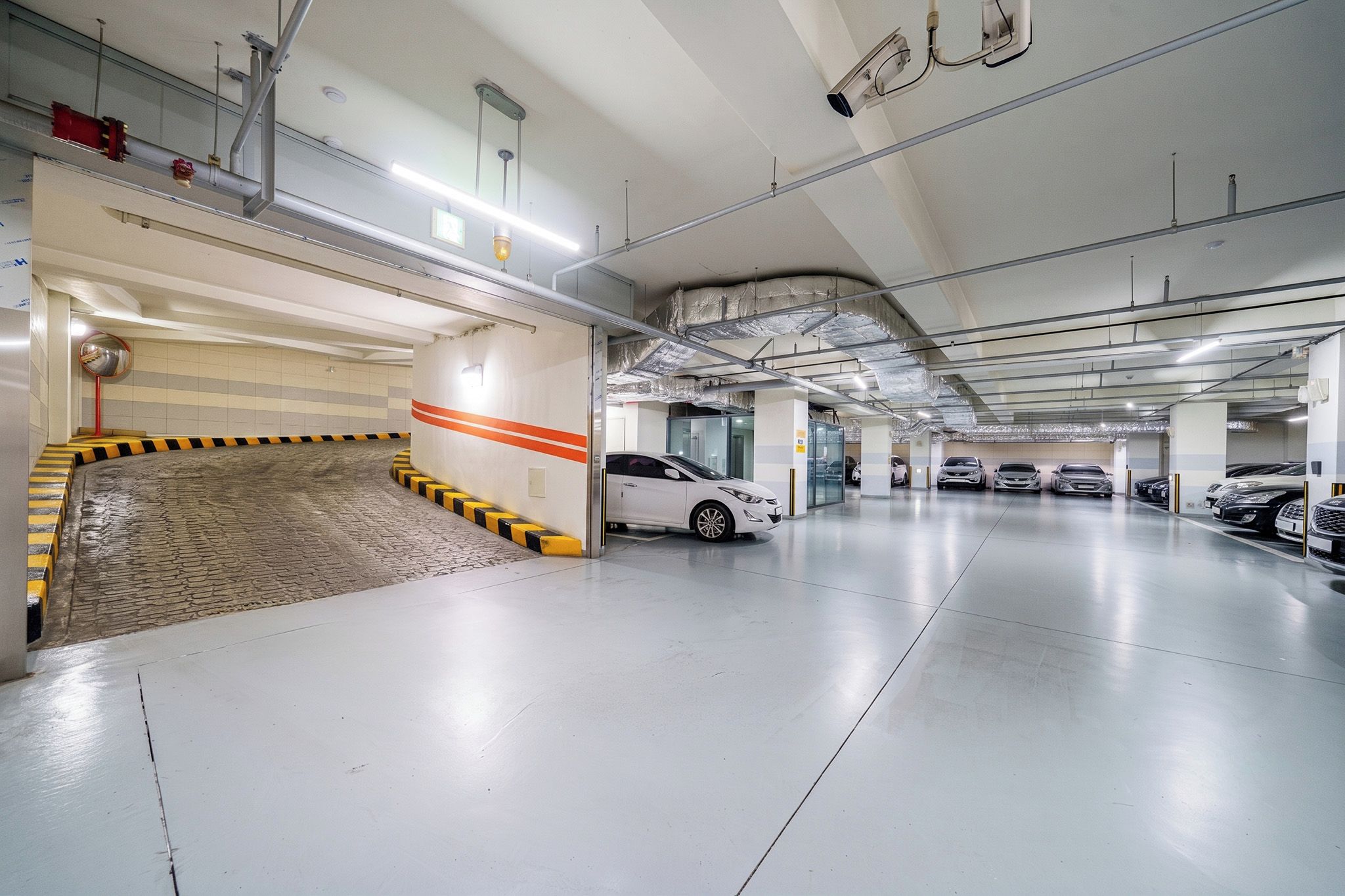 A multi-level parking garage with a ramp leading to a lower level, multiple parking spaces, and a clean, well-lit environment.