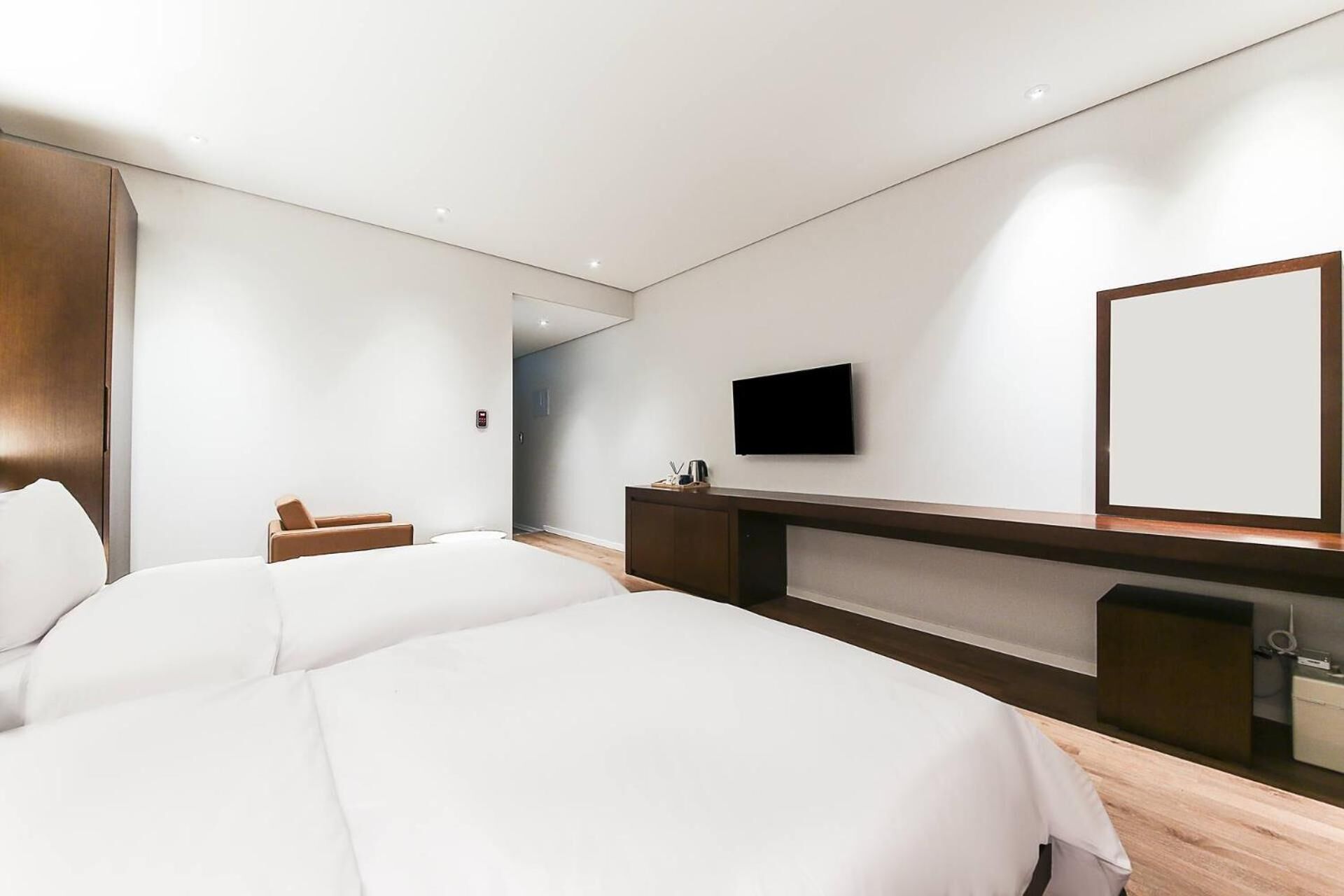 A modern hotel room with a large bed, a desk with a flat-screen TV, and a mirror.