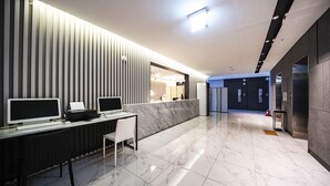 A modern reception area with a reception desk, computers, and a marble floor. - Golden River Hotel (Gwangmyeong)