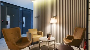 A modern lobby with a round table, two armchairs, and a sofa. - Golden River Hotel (Gwangmyeong)
