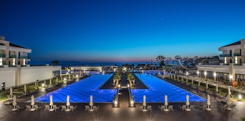Una piscina techada, una piscina al aire libre, sombrillas