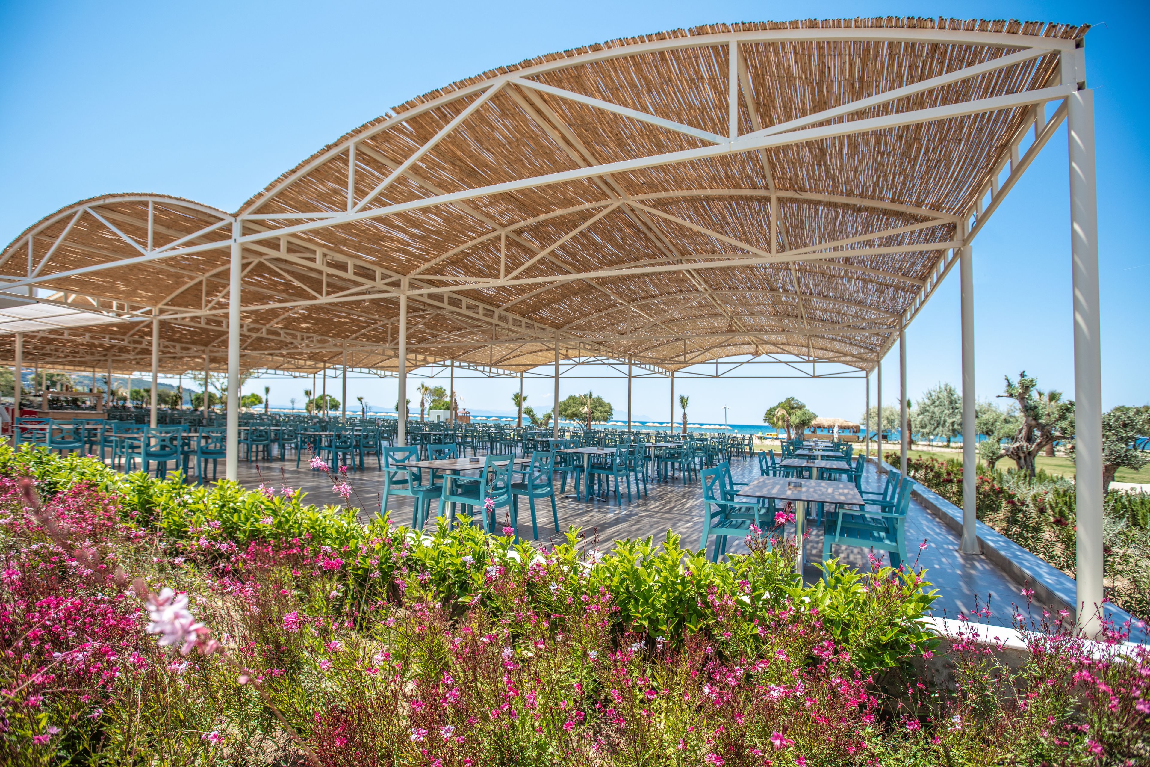 An outdoor dining area with a covered seating arrangement and a poolside view.