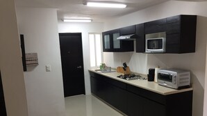 Uma cozinha moderna com armários pretos, um fogão de aço inoxidável, micro-ondas e forno embutido.